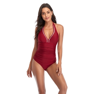 Detail of dark red one-piece swimsuit featuring a deep V-neck and ruched slimming texture