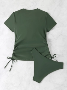 Flat lay detail of olive green two-piece swimsuit with side drawstrings on marble surface