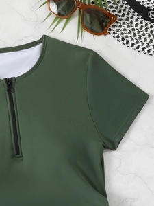Detailed view of dark green short sleeve swimwear with front zipper on marble background