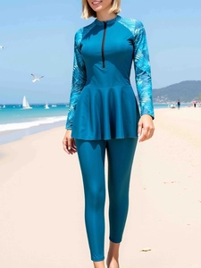 Détail d'un maillot de bain bleu à manches longues avec imprimé tropical et fermeture éclair