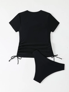 Flat lay of black two-piece swimsuit with short sleeve top and drawstring details