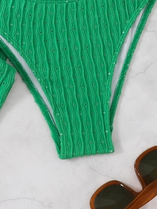 Detail of green bikini fabric showing vertical ribbed texture and laser-cut eyelet design