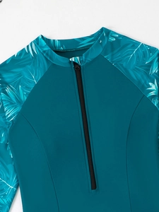 Détail de l'imprimé palmier tropical et de la fermeture éclair sur le maillot bleu