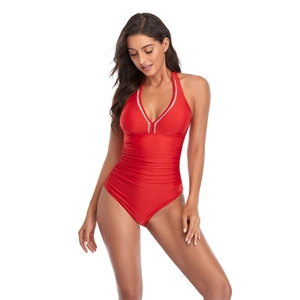 Detailed view of red one-piece swimsuit featuring a V-neck and slimming pleated waist texture