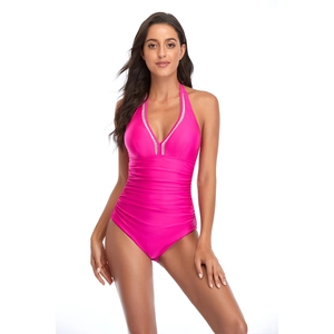 Close-up of pink one-piece swimsuit with V-neckline and decorative polka dot trim detail
