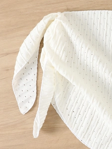 Detailed close-up of white tie-up bikini fabric with wave texture and eyelet embroidery