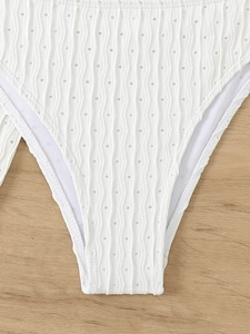 Detail of white high-waisted bikini bottom with textured wave pattern and eyelet details