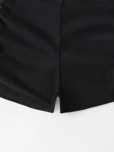 Detail view of black high-waist swim shorts with premium stitching and elastic fabric