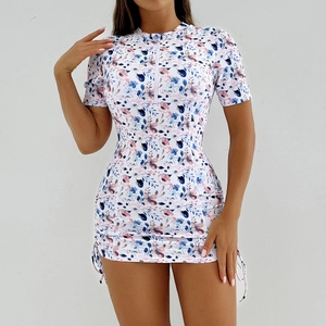 Vue avant du maillot de bain sport à fleurs, manches courtes, col zippé et jupe à cordon