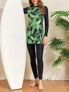 Detail of two-piece long sleeve swimwear with tropical leaf print and black leggings