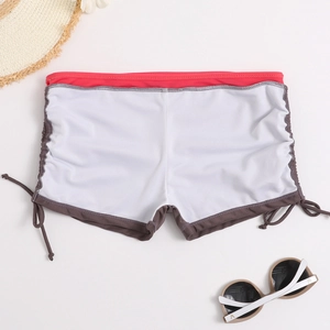 Flat lay of white high-waisted bikini bottoms with red waistband and drawstring sides