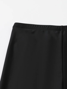 Detail view of elastic waistband and stitching on black athletic swimwear shorts