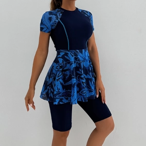 Detail of short sleeve swim top with floral peplum and navy high waist surf shorts