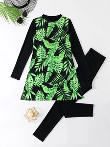 Detail view of long-sleeve swimwear with green palm leaf print and matching black leggings