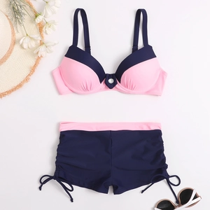 Flat lay of pink and navy two-piece bikini with decorative ring and drawstring side details