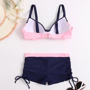 Flat lay of pink and navy two-piece bikini set with adjustable drawstring and sun hat