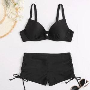 Flat lay of black two-piece bikini with silver buckle top and high-waisted drawstring bottoms