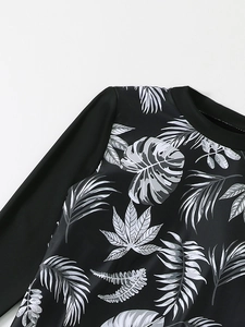 Detail of round neckline and tropical leaf print on black long-sleeve swimwear top