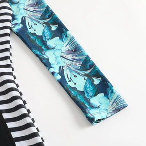 Détail de manche de maillot avec imprimé fleuri bleu et empiècement rayé noir et blanc