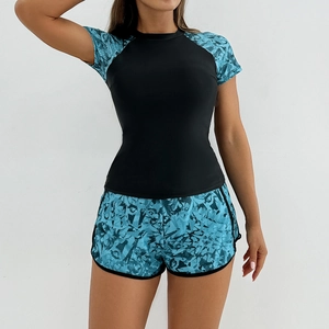 Detail of short-sleeve sports swimsuit featuring raglan sleeves and blue abstract patterns