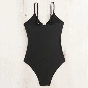 Detailed top view of black one-piece swimsuit with thin straps and gold V-shaped buckle