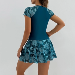 Detail view of the back of a two-piece swimsuit with tropical print sleeves and pleated skirt