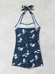 Detailed close-up of dark blue one-piece swimsuit with floral print and halter neck tie