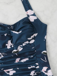 Detailed view of floral one-piece swimsuit with ruched fabric and dark teal print