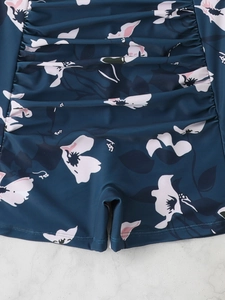 Close-up of high-waist floral swim bottoms with side ruching in navy blue and pink
