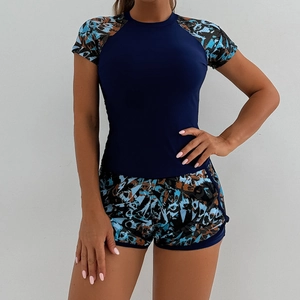 Detail of two-piece tankini set featuring blue short-sleeve top and camo print athletic shorts