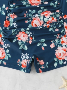 Detail of navy one-piece swimsuit with pink rose print and ruched sides for beachwear