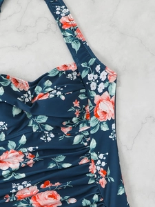 Detail of floral one-piece swimsuit featuring ruched fabric and pink rose patterns