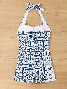 Detail of blue geometric print one-piece halter swimsuit on light wood background