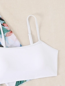 Detail of white bikini top with adjustable strap and tropical floral print fabric