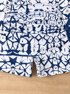 Detail of high-stretch swimsuit bottoms with navy star pattern and side ruching texture
