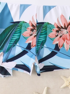 Detailed view of floral bikini bottoms with tropical pink flowers on sandy beach background