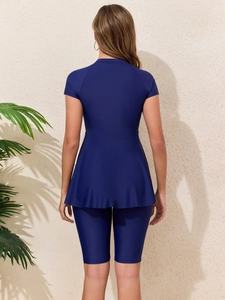 Back view of a modest navy blue two-piece swimsuit with short sleeves and a swim skirt