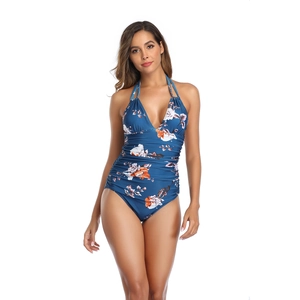 Detail view of ruched waist and floral print on a navy blue halter neck swimsuit