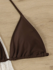 Close-up of dark brown bikini top featuring gathered cup details and fine stitching on wood