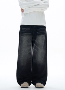 Detail of high street loose washed black jeans featuring whiskering and retro faded texture