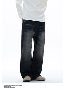 Detail of washed black denim with distressed cat-whisker patterns and loose straight leg cut