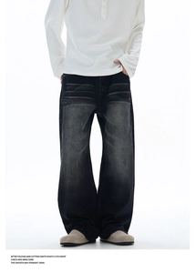 Detail of washed black distressed wide-leg jeans with cat scratch texture and loose fit