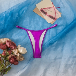 Flachbild von glänzendem lila Metallic-Tanga-Bikini mit rosa Sonnenbrille und Rosen