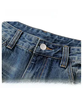 Dettaglio jeans blu scuro lavato con cuciture arancioni e bottone in argento lucido