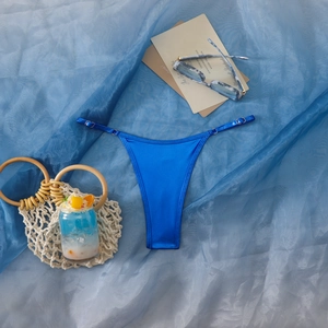 Detailansicht der glänzenden blauen Satin-Bikininhose mit verstellbaren Metallringen