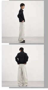 Détail du pantalon large beige et de la veste noire minimaliste en coupe ajustée
