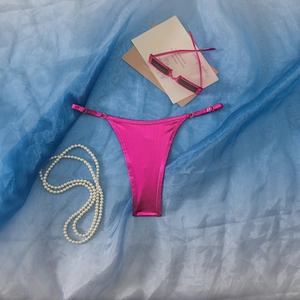 Detailansicht der metallischen rosaroten Bikinihose mit verstellbaren Trägern und Goldfinish