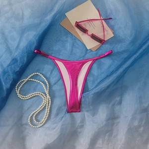 Nahaufnahme der metallic-rosapinkfarbenen Bikini-Hose mit Glanzoptik und dünnen Riemchen