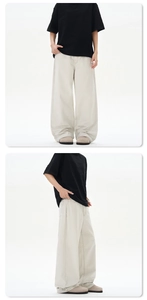 Detail view of loose-fit straight white denim trousers showing front pocket and side drape