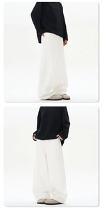 Détail d'un pantalon large blanc ample porté avec des chaussures plates en cuir beige